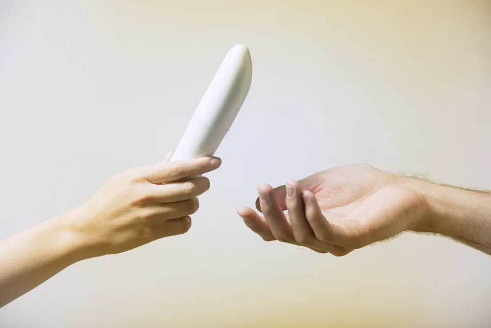Close up of woman's hand, handing a man's hand a vibrator